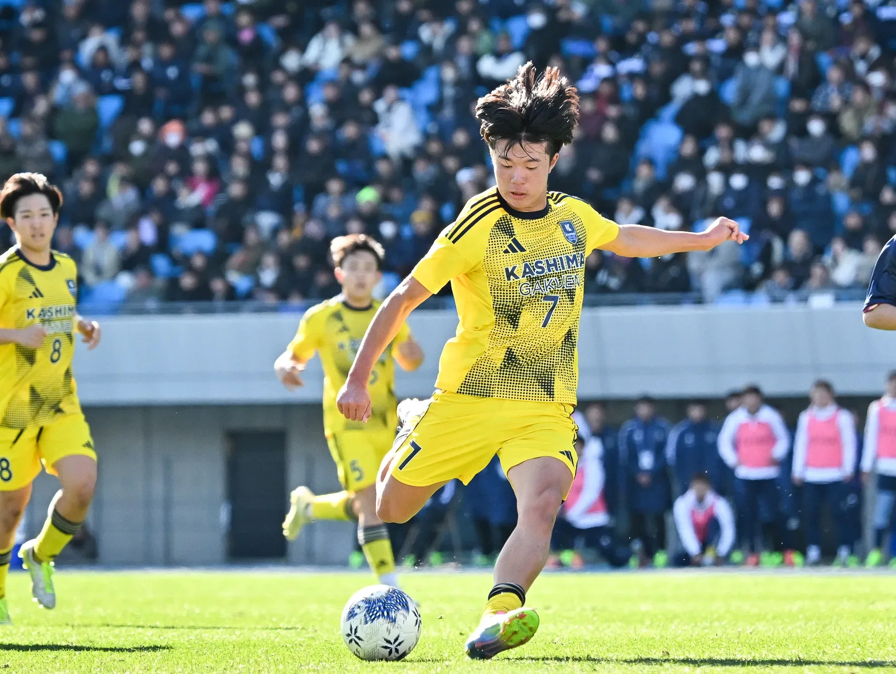 満員のスタンドを背にシュートを放つ鹿島学園高等学校の選手