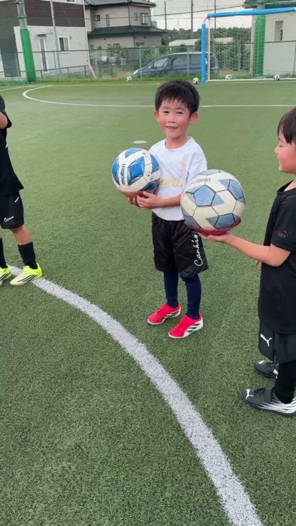幼児クラスのお子さまが、サッカーボールを両手で持って立っている様子